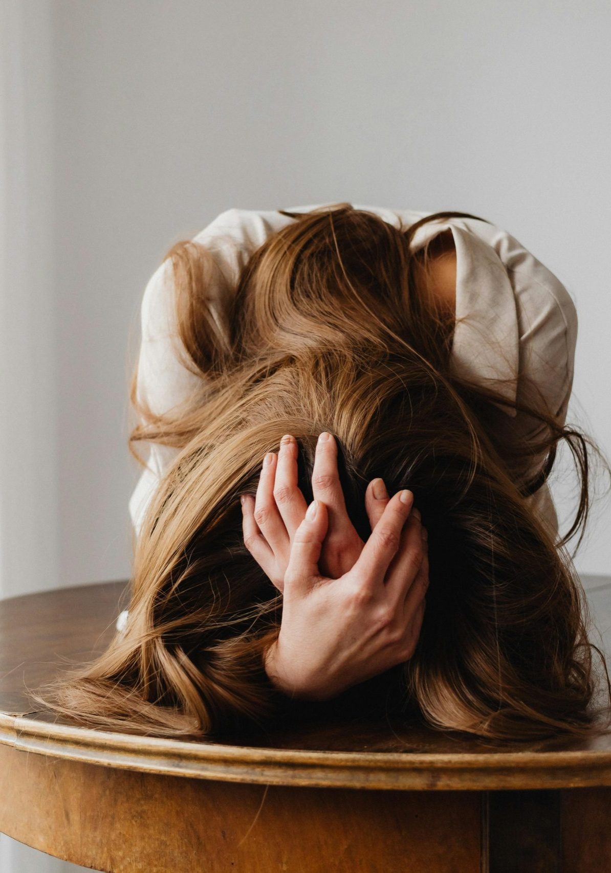 A woman showing despair with her head down on a table, indicating stress.